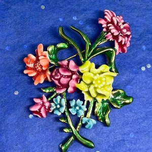May include: A colorful enamel flower brooch with pink, yellow, green, blue, and orange flowers. The brooch is made of metal and has a gold finish.