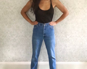 May include: A pair of light blue high-waisted jeans with a straight leg fit. The jeans are worn with a brown tank top.