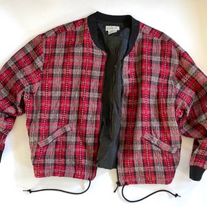 May include: A red, black, and gray plaid bomber jacket with a zipper closure and a drawstring at the bottom. The jacket has two pockets on the front.