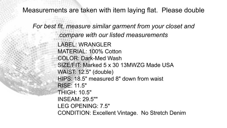 May include: Measurements for a vintage Wrangler denim jean in dark wash. The measurements are listed in inches: waist 12.5, hips 18.5, rise 11.5, thigh 10.5, inseam 29.5, leg opening 7.5. The condition is excellent vintage, no stretch denim.
