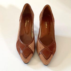 May include: A pair of brown suede and woven leather heeled shoes with a pointed toe. The shoes have a geometric pattern and the brand name "Claudia London" is printed on the insole.