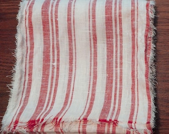 May include: White linen fabric with red stripes. The fabric has a frayed edge.