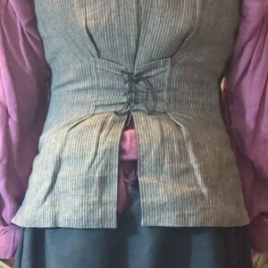 May include: A gray and white striped vest with a black lace-up back. The vest is made of a linen-like fabric and has a fitted silhouette.