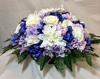 Headstone saddle. Purple and white. White roses, dahlia; light & deep purple hydrangea; lavender heather sprigs. 22x10”. Faux flowers.