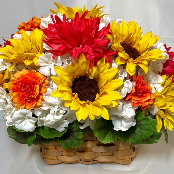 Sunflower floral. Sunflowers, dahlia, marigold, and geraniums in a woven handle basket. 13x15”. Faux flowers and leaves. Floral protectant.