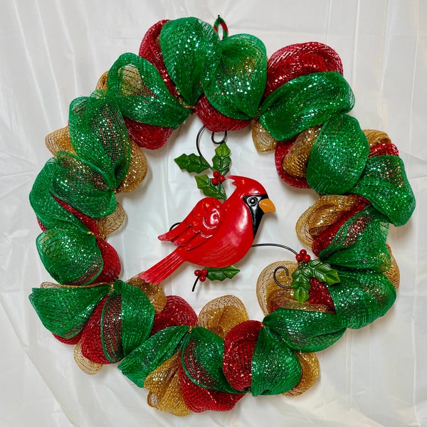 Cardinal mesh wreath. Red metal cardinal on holly leaf branches. Red, green, gold deco mesh on 18” wire frame. 21” wreath.