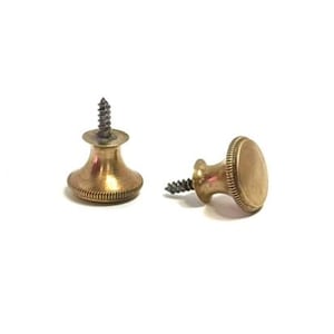 May include: Two brass cabinet knobs with a circular, flat top and a flared, ribbed base. Each knob features a central metal screw protruding from the back, designed for mounting. The metal has a warm, metallic gold finish with visible texture.