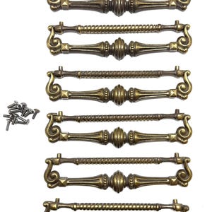 May include: A set of eight antique brass drawer pulls with decorative scrollwork and a central, ribbed design. The pulls have a warm, aged finish and come with small mounting screws. The overall design is ornate and vintage-inspired, suitable for furniture restoration.