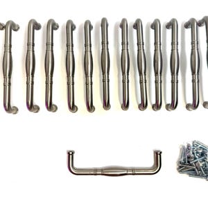 May include: A set of fifteen silver-toned metal cabinet pulls, each featuring a central rounded bulge and two horizontal rings. One pull is positioned horizontally below the vertical row, accompanied by a small pile of silver metal mounting screws.
