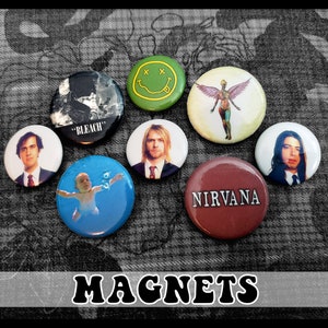 May include: Set of eight round magnets featuring various band logos and images. The magnets include Nirvana, Bleach, a smiley face, a baby swimming, and a figure with wings. The magnets are all approximately 2 inches in diameter.