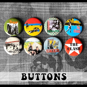 May include: Nine round The Clash band buttons. The buttons feature different album covers and band logos. The buttons are red, yellow, blue, green, black, and white.