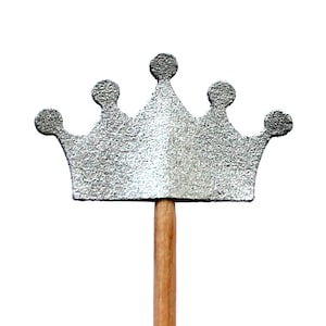 Könnte beinhalten: Eine silberne Glitzerkrone auf einem Holzstab. Die Krone hat fünf Zacken und ist eine beliebte Dekoration für Partys und Feiern.