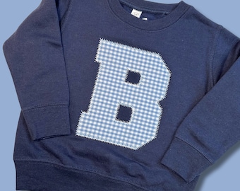 May include: A navy blue sweatshirt with a large blue and white gingham letter "B" sewn on the front.