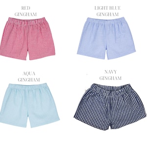 May include: Four pairs of gingham shorts in different colors: red, light blue, aqua, and navy. Each pair has an elastic waistband and a checkered pattern.