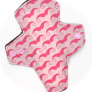 Puede incluir: Compresa de tela reutilizable rosa con un patrón de bigote y botones a presión rosas.