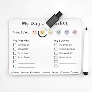 May include: White dry-erase board with a checklist for a daily routine. The board has sections for "My Morning" and "My Evening" with checkboxes for tasks like "Clothes on", "Breakfast", "Brush Hair", "Brush Teeth", and "Pyjamas on". The board also includes a section for "Today I feel" with five emoji faces.
