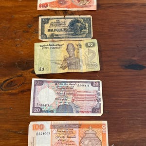 Puede incluir: Una colección de billetes antiguos de varios países, incluyendo Ringgit de Malasia, Half Gulden, Piastras egipcias y Rupias de Sri Lanka. Los billetes muestran retratos, diseños intrincados y denominaciones.