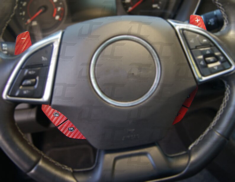 May include: A black leather steering wheel with red carbon fiber paddle shifters. The paddle shifters are labeled with the letters "FM".