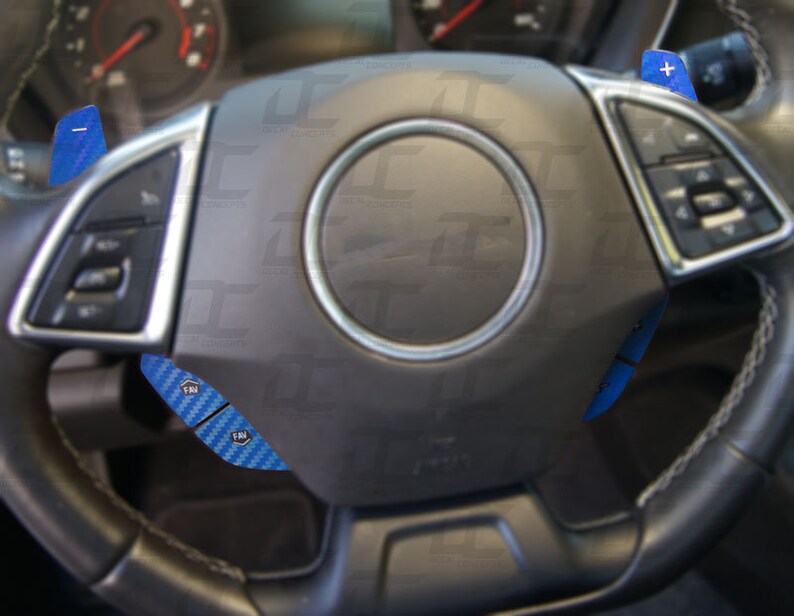 May include: A black leather steering wheel with blue carbon fiber paddle shifters. The steering wheel has a silver trim and a black center with a silver ring around it.