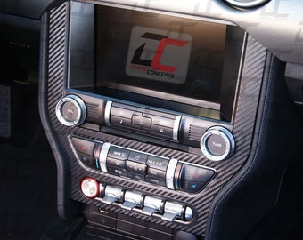 May include: A black car interior with a carbon fiber dashboard and a touchscreen display. The display shows the logo "Decal Concepts". The dashboard has various buttons and knobs, including volume, tune, and climate control.