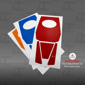 May include: Three decal sticker sheets for a car interior. The sheets are white with red, blue, and orange carbon fiber designs. The text on the bottom sheet reads "PLEASE READ This is decal sticker kit, Not a hard cover."