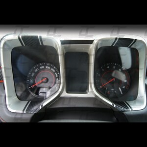 May include: A close-up of a car's dashboard with two gauges. The gauges are surrounded by a silver trim with black carbon fibre accents. The speedometer reads up to 160 mph and the tachometer reads up to 9,000 RPM.