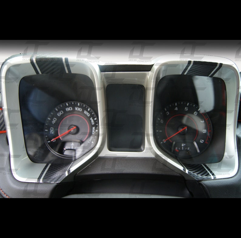 May include: A close-up of a car's dashboard with two gauges. The gauges are surrounded by a silver trim with black carbon fibre accents. The speedometer reads up to 160 mph and the tachometer reads up to 9,000 RPM.