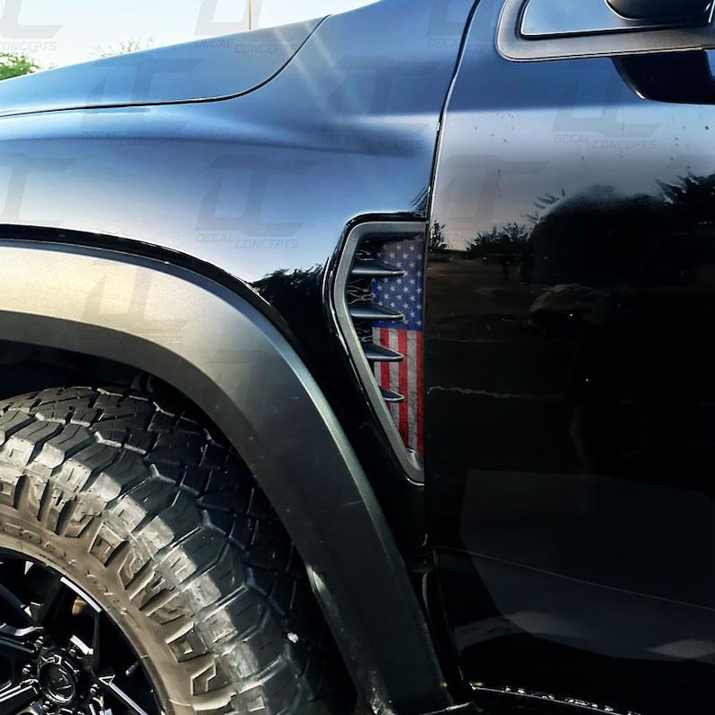 K&ouml;nnte beinhalten: Schwarzes Fahrzeug mit einem Seitenl&uuml;fter mit amerikanischem Flaggen-Design. Der L&uuml;fter befindet sich in der N&auml;he des Vorderrads und ist von einer schwarzen Verkleidung umrahmt. Der Reifen hat eine schwarze Felge und ein robustes Profil.