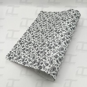 May include: White vinyl with a black paisley pattern. The pattern is a repeating design of paisley shapes.