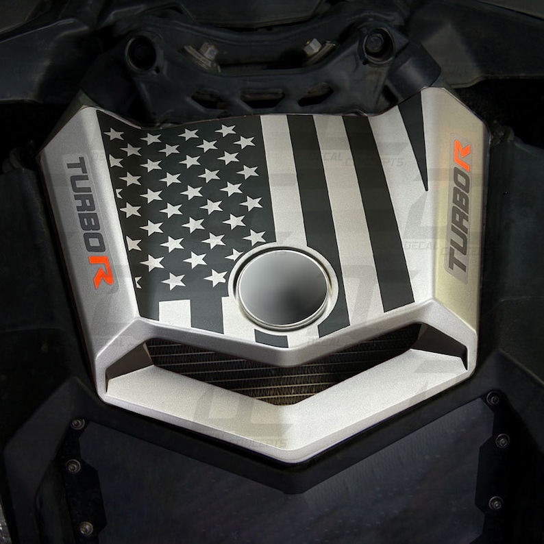 May include: A black and white American flag graphic decal with the word "TURBOR" on either side. The decal is on a silver engine cover.