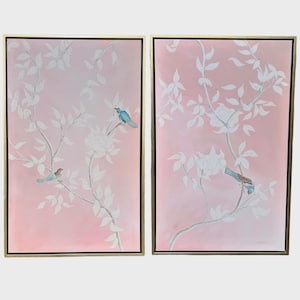 May include: A pair of rectangular wall art pieces in gold frames, featuring a soft pink background with white painted branches, leaves, and flowers. Each panel depicts small blue birds perched on the branches in a delicate, nature-inspired composition.