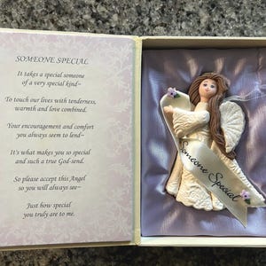 May include: A decorative angel figurine in a gift box. The angel is wearing a white gown and has long brown hair. A banner reading "Someone Special" is held by the angel. The box contains a poem about someone special.