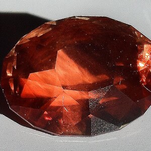 May include: A large, faceted, reddish-brown gemstone with a smooth, polished surface.