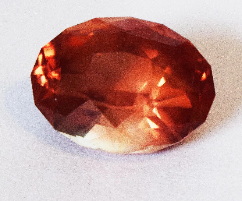 May include: A large, faceted, red-orange gemstone with a slightly cloudy appearance.