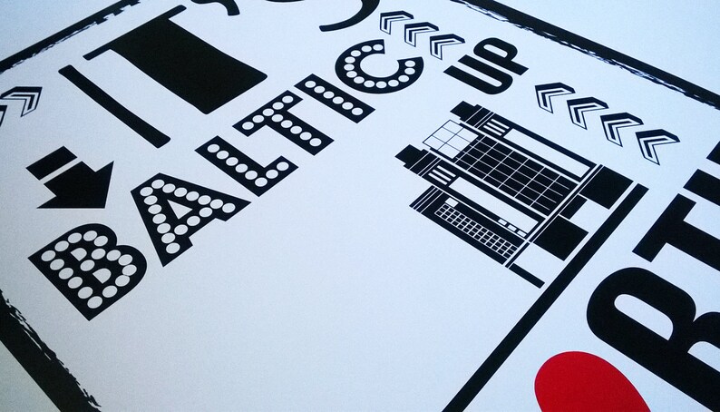 以下が含まれることがあります： 「I &hearts; BATIC」というテキストと、スタイリッシュな建物のイラストが描かれた白黒のグラフィックプリント。テキストは太字で、文字の周りに白い点が付いています。建物は、窓がたくさんある背の高い長方形の構造です。右と下に指し示す矢印があります。