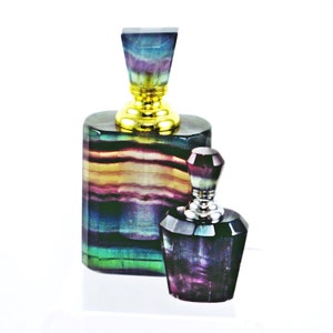 Könnte beinhalten: Zwei dekorative Parfümflacons aus schillerndem Fluoritkristall. Die größere Flasche hat einen goldenen Verschluss und die kleinere einen silbernen Verschluss.