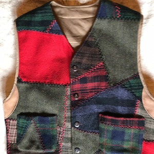 May include: A patchwork vest featuring a variety of fabrics in red, green, blue, and brown. The vest has a V-neck, two pockets, and a button-up front. The edges are trimmed with a light brown material.