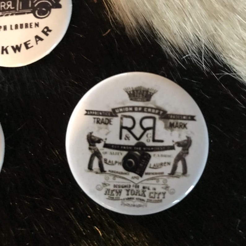K&ouml;nnte beinhalten: Ein schwarz-wei&szlig;er Knopf mit einem Vintage-Design, das den Text "Union of Craft" und "Trade Mark" um die Initialen "R&Co" herum zeigt. Der Text "Designed for WPL in New York City" ist ebenfalls enthalten.