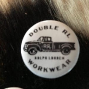 K&ouml;nnte beinhalten: Wei&szlig;er Knopf mit schwarzem Text und einer schwarz-wei&szlig;en Illustration eines Pick-up-Trucks. Der Text lautet "Double RL Ralph Lauren Workwear".
