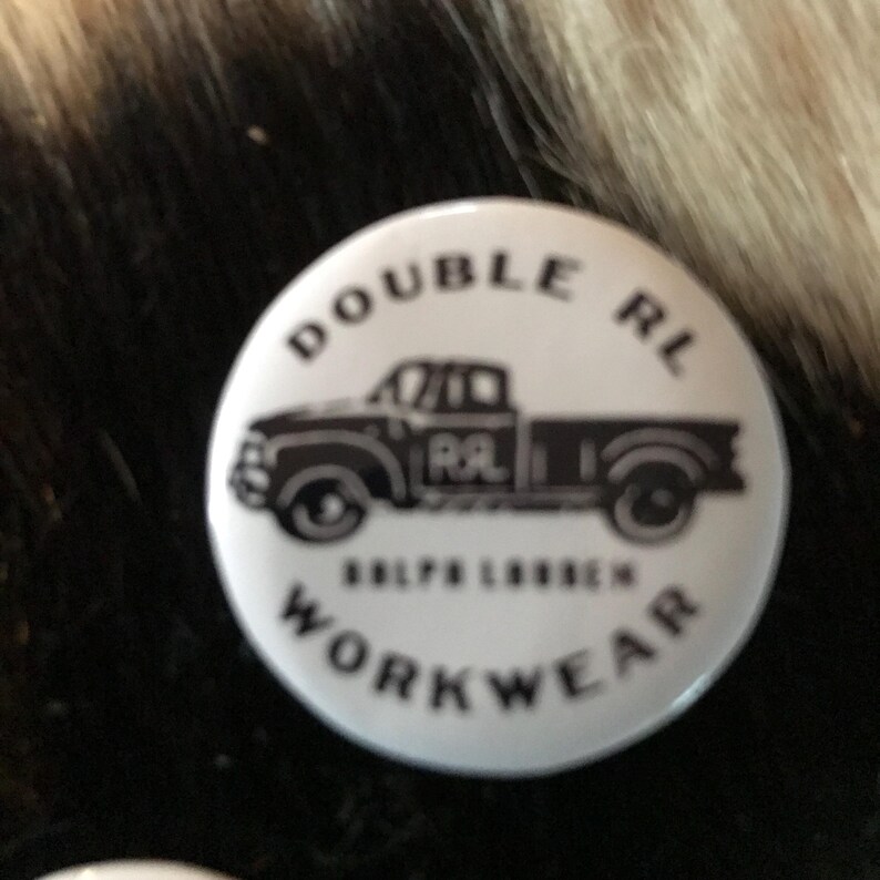 K&ouml;nnte beinhalten: Wei&szlig;er Knopf mit schwarzem Text und einer schwarz-wei&szlig;en Illustration eines Pick-up-Trucks. Der Text lautet "Double RL Ralph Lauren Workwear".