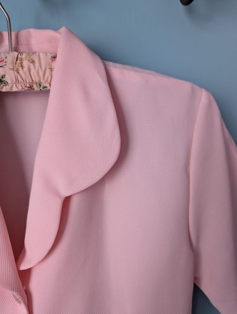 May include: A pink collared blouse with a rounded collar. The collar is folded over and has a scalloped edge.
