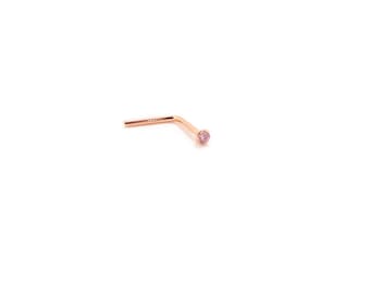 Puede incluir: Un piercing de nariz de oro rosa con una pequeña gema rosa redonda. La joya en forma de L está sobre un fondo blanco.