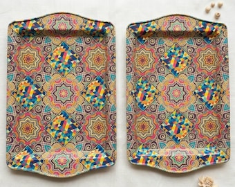 May include: Two rectangular metal trays featuring a vibrant, repeating geometric pattern. The design includes colorful diamonds, star-like floral motifs, and intricate swirls in shades of yellow, pink, blue, and orange on a dark background.
