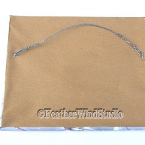 May include: The back of a rectangular framed artwork. The frame is wrapped in brown paper with a silver wire for hanging. The text "&copy;Feather WindStudio" is printed on the bottom right corner.