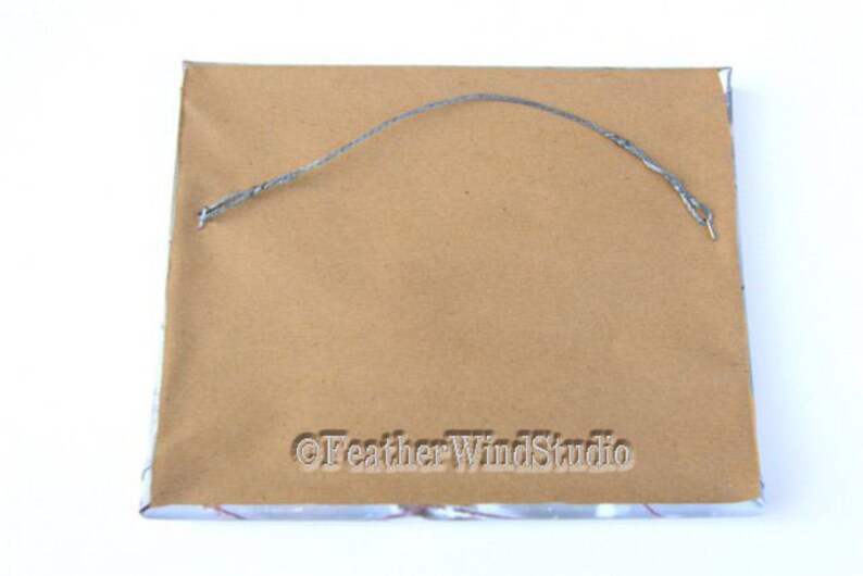 May include: The back of a rectangular framed artwork. The frame is wrapped in brown paper with a silver wire for hanging. The text "&copy;Feather WindStudio" is printed on the bottom right corner.