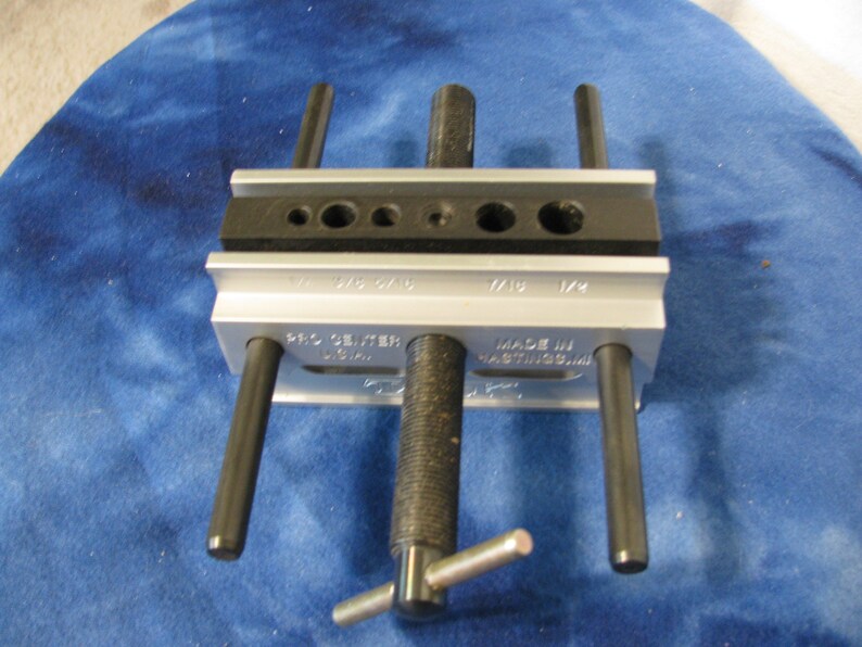 May include: A silver and black Pro Center tool with multiple holes and black rods. The tool has the text "PRO CENTER USA" and "MADE IN HASTINGS, MI" printed on it. The tool is designed for precision work.