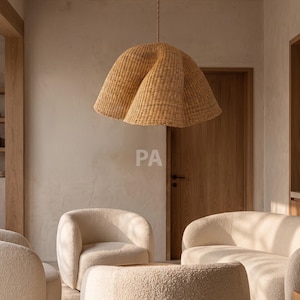 May include: A large, bell-shaped pendant light fixture crafted from woven light brown natural fibers, featuring a textured, organic, undulating rim. The lamp hangs from a thin cord, suspended above a set of cream-colored, textured fabric chairs.