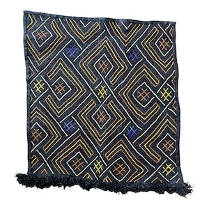 May include: Black and white textile with a geometric pattern in orange, yellow, and purple. The textile has a fringe border.