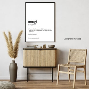 Könnte beinhalten: Gerahmter weißer Druck mit der Definition von "unagi" in schwarzem Text. Der Druck wird über einem Holzschrank mit einer Vase mit getrockneten Pflanzen, einer dekorativen Schale und einem gewebten Stuhl angezeigt.
