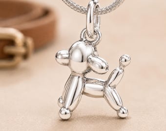 May include: A polished silver-toned pendant shaped like a balloon dog, featuring a smooth, reflective surface and rounded limbs. The pendant is suspended from a matching silver-toned chain, showcasing a minimalist design with a clear, metallic finish.